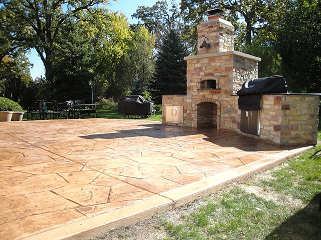Stamped concrete patio with a stone outdoor fireplace and built-in grill, poured by Taber Builders