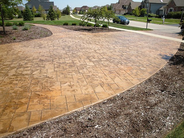 Wide tan stamped concrete driveway in a suburban neighborhood